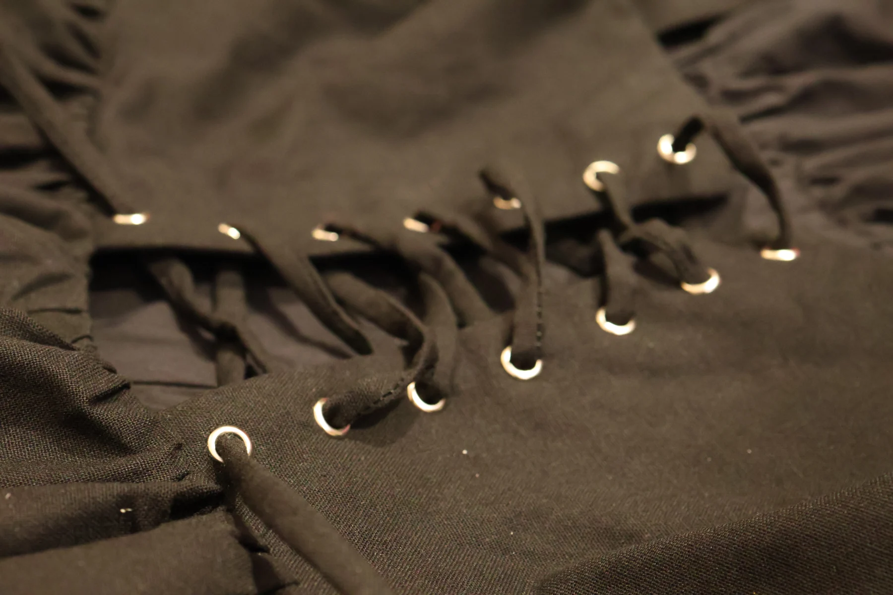 Black fabric lacing through silver-tone eyelets on the adjustable back of a gothic dress made by Metrodress
